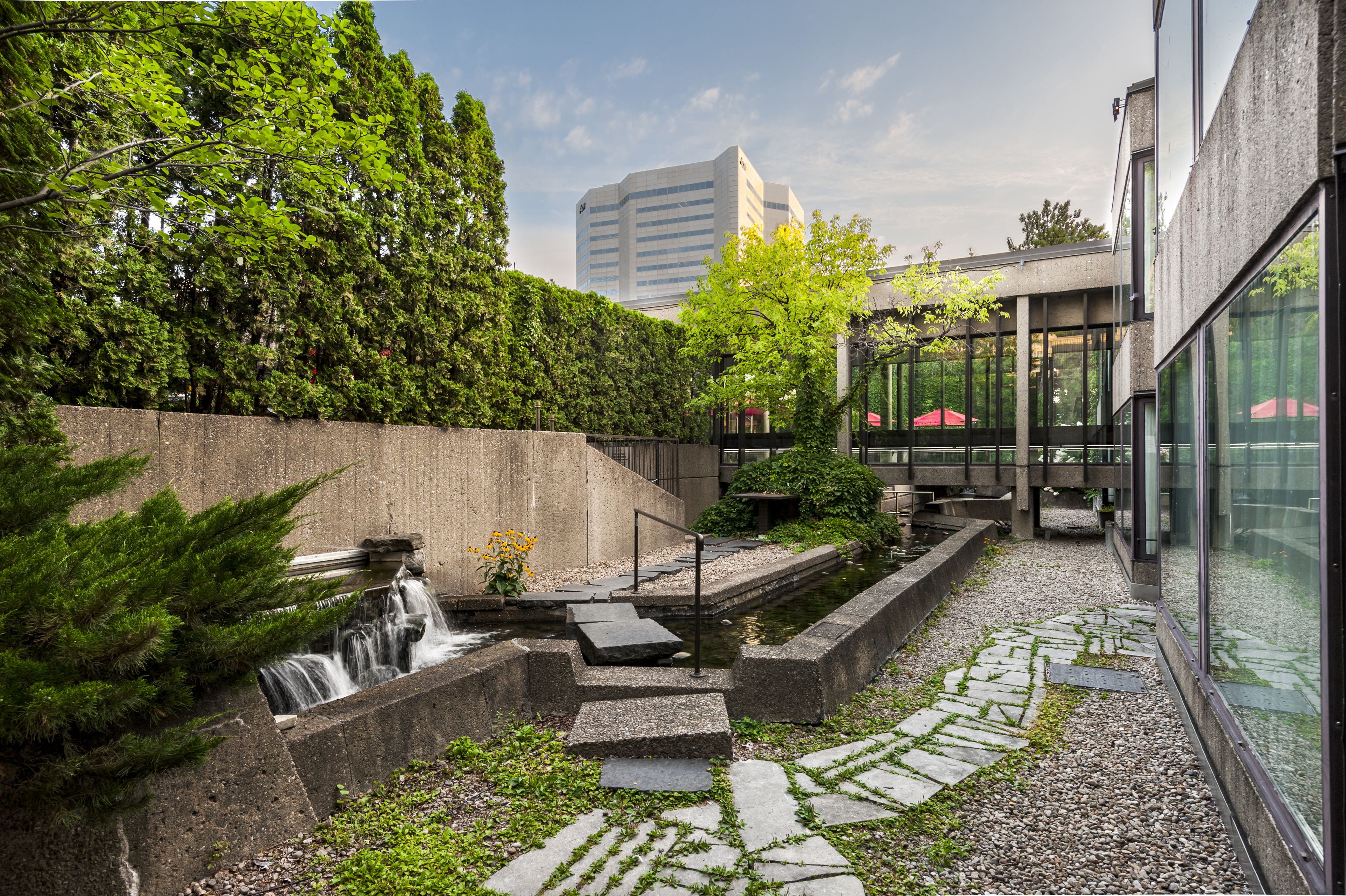 A courtyard with a water feature, stone steps, and a glass building in the background.
