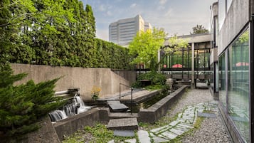 Un patio con una fuente de agua, escalones de piedra y un edificio de cristal al fondo.