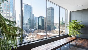 A modern interior with a large window offering a city view, a wooden bench, and a potted plant. - Hotel Bonaventure Montreal (Montreal)