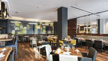 Ein modernes Restaurant mit Holzböden, verschiedenen Essbereichen und zeitgemäßer Beleuchtung.