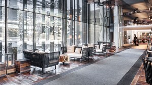 A modern interior with large windows, a seating area with sofas and chairs, and a visible staircase. - Hotel Bonaventure Montreal (Montreal)