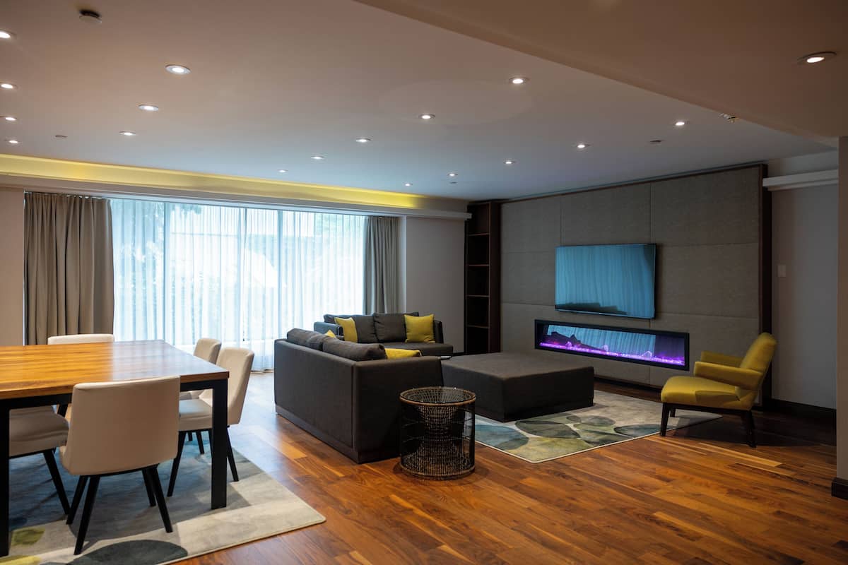 A modern living room with a wooden dining table, sofa, and armchairs.