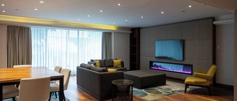 A modern living room with a wooden dining table, sofa, and armchairs.