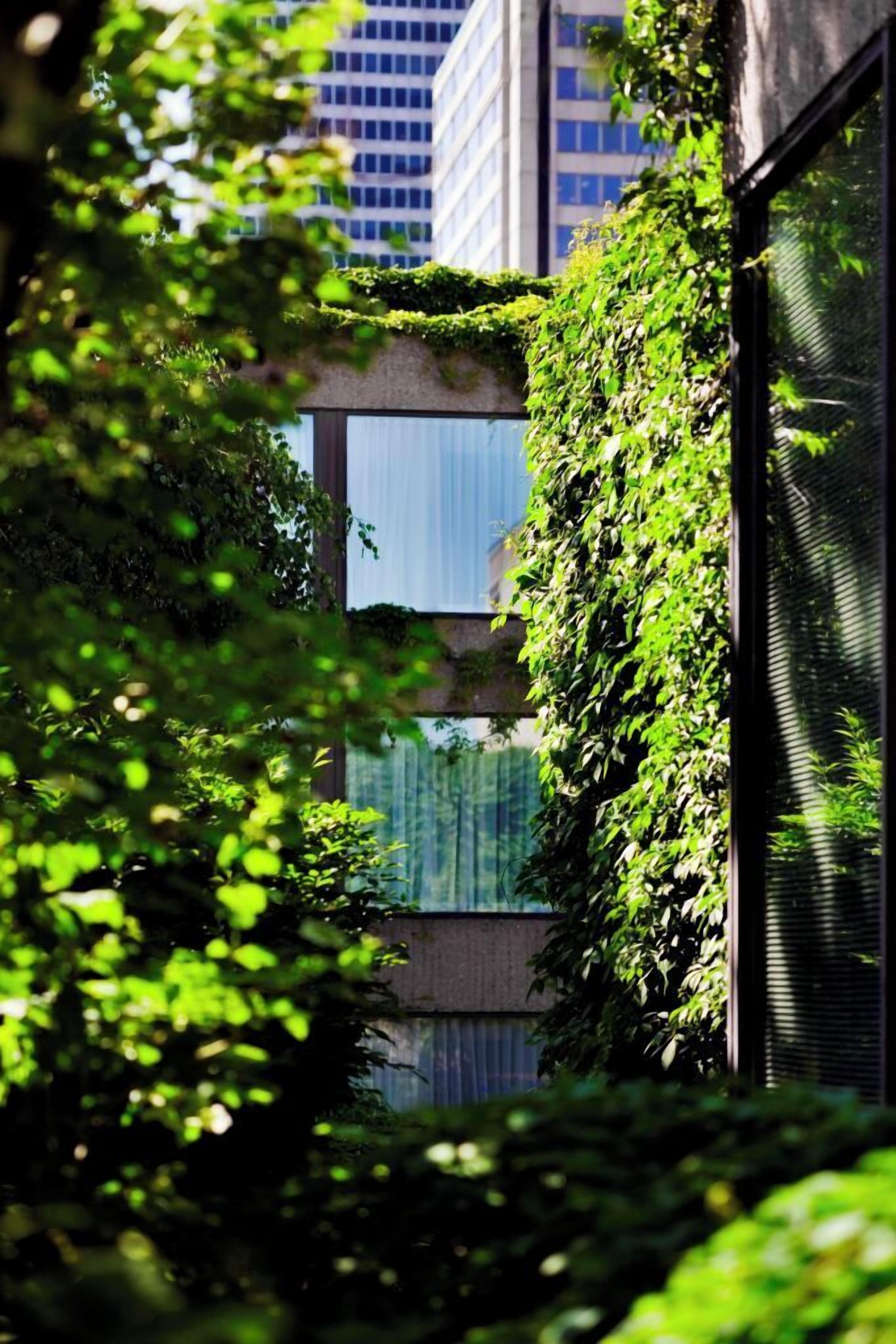 Ein Gebäude mit modernem Design, mit Glasfassade und einer vertikalen Begrünung an einer Seite.
