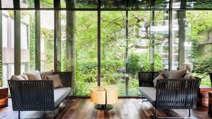 A modern room with two black sofas and a central lamp, large windows offering a view of greenery outside. - Hotel Bonaventure Montreal (Montreal)