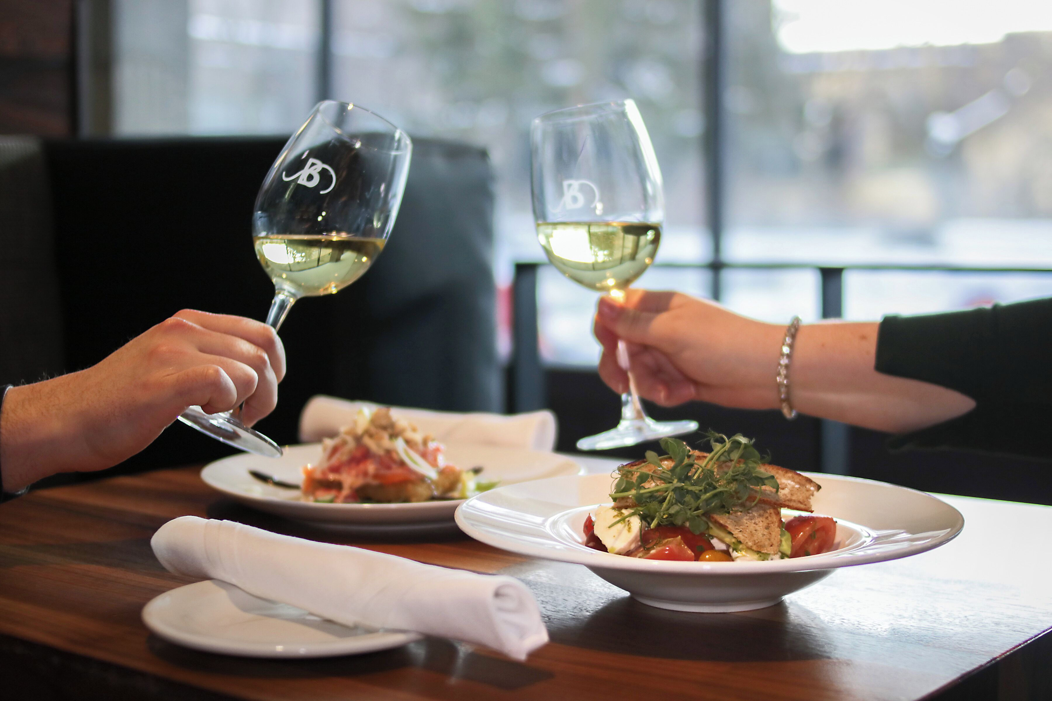 A dining table with two plates of food and two wine glasses.