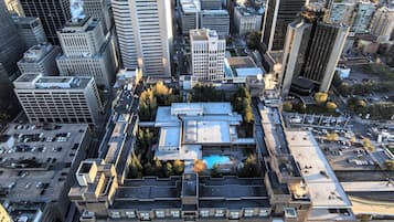 An aerial view of a cityscape with a prominent building featuring a rooftop garden and a parking lot.