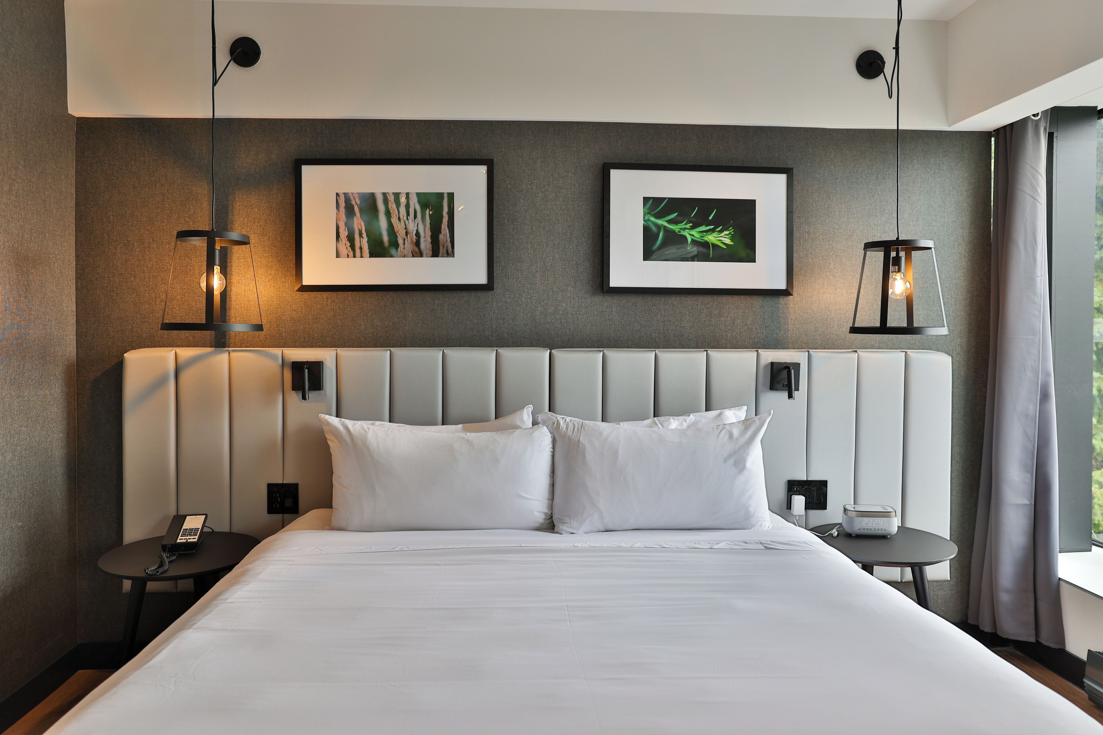 Une chambre d’hôtel moderne avec un grand lit, deux tables de chevet et des œuvres d’art accrochées au mur.