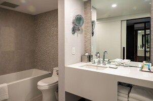 A modern bathroom with a bathtub, toilet, and a vanity with a mirror and sink.