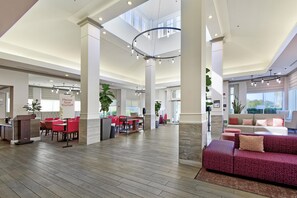 A spacious lobby with a high ceiling, multiple seating areas, and a central column. - Hilton Garden Inn Livermore (Livermore)