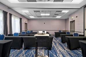 A conference room with a projector, rows of chairs, an exit sign, and a carpeted floor. - Hilton Garden Inn Livermore (Livermore)