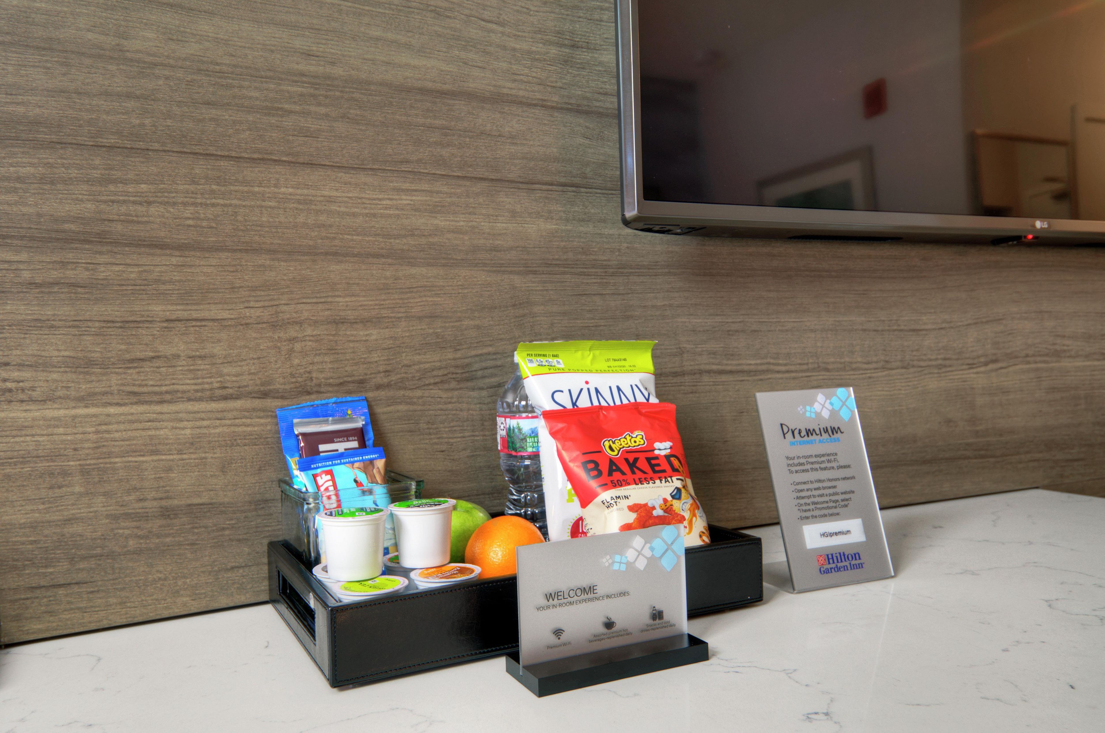 Un mini refrigerador de hotel con refrigerios, bebidas y un cartel de acceso a internet.