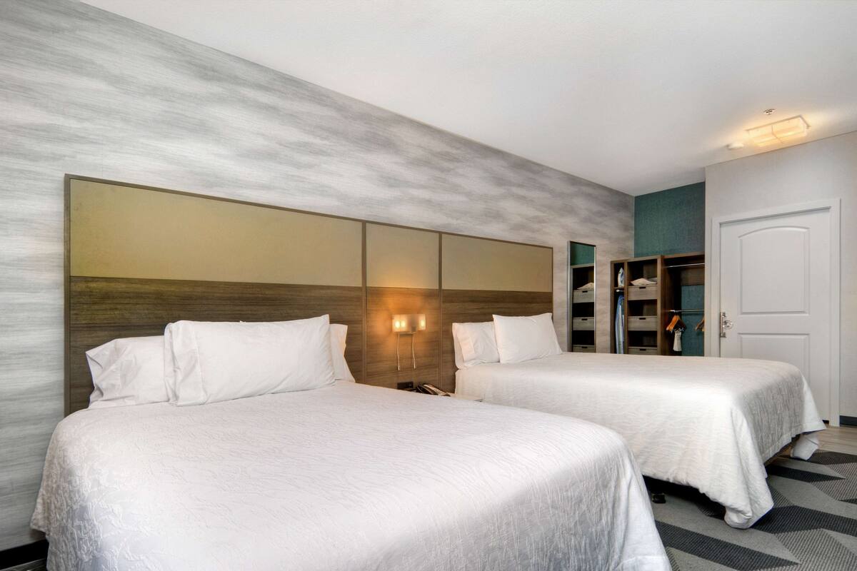 Habitación de hotel con dos camas, un espejo grande y un armario.