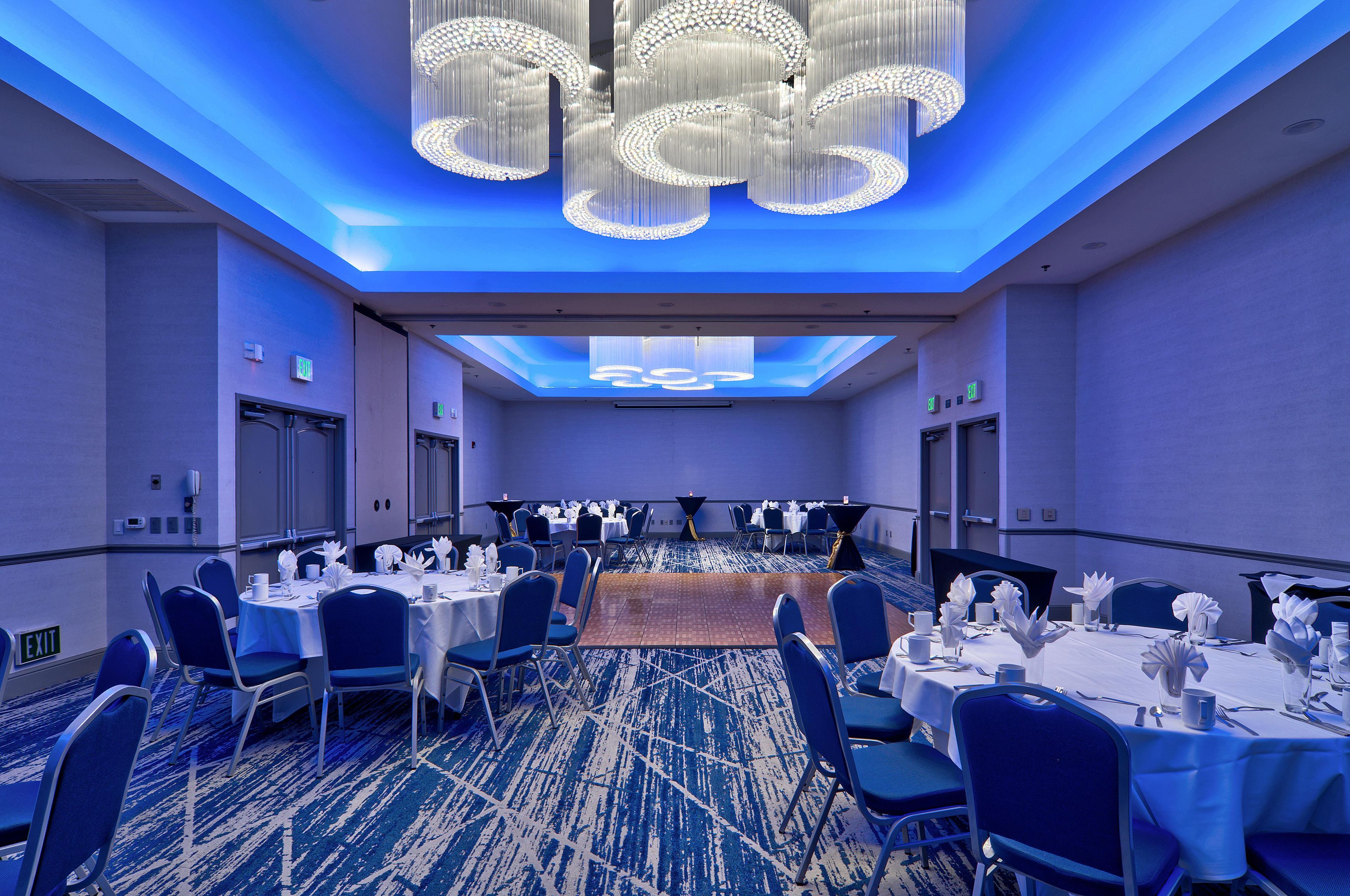 A conference room with round tables, chairs, and a blue carpet.