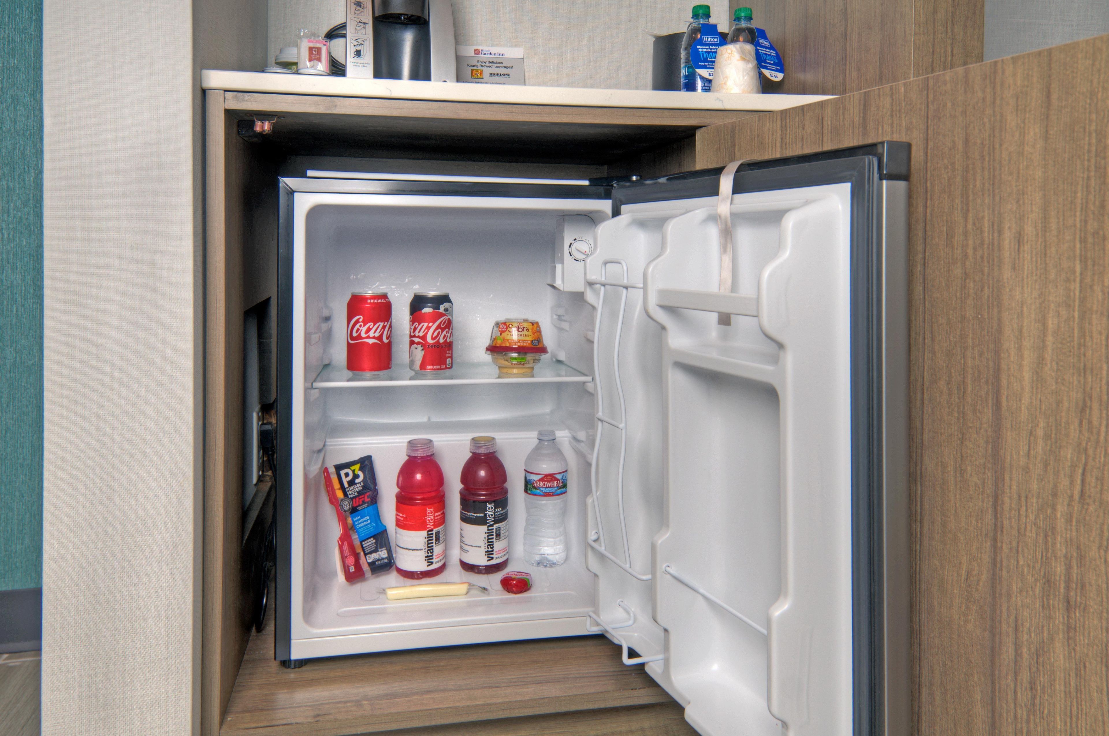A compact refrigerator with a freezer compartment on top, containing various beverages and condiments.