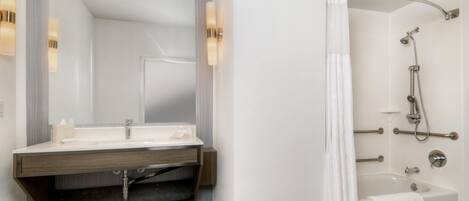 A modern bathroom with a vanity, mirror, shower, and bathtub.