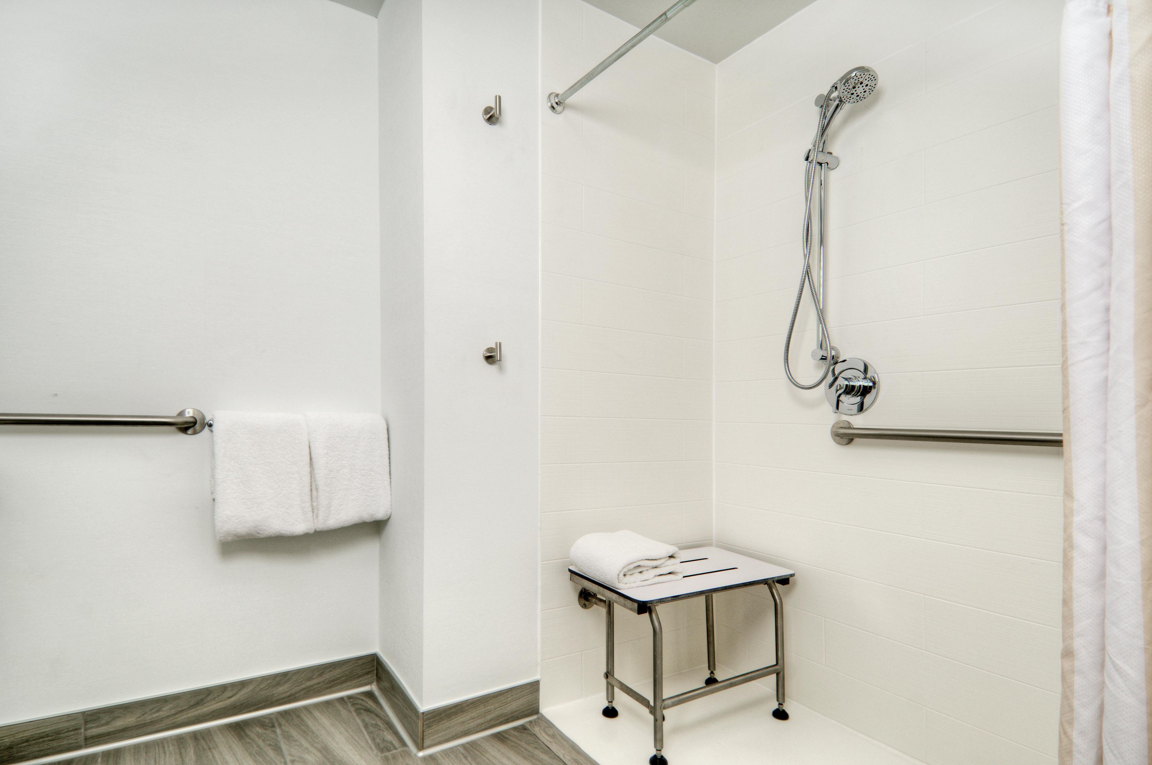 Un baño con ducha, perchero y una pequeña mesa.