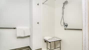 Un baño con ducha, perchero y una pequeña mesa.