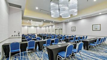 Un salón de conferencias con filas de mesas y sillas, equipado con tarjetas de identificación y un candelabro.