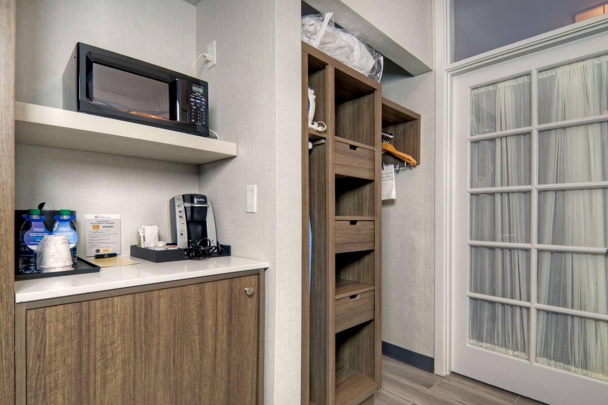 Una kitchenette equipada con microondas, cafetera y agua embotellada.