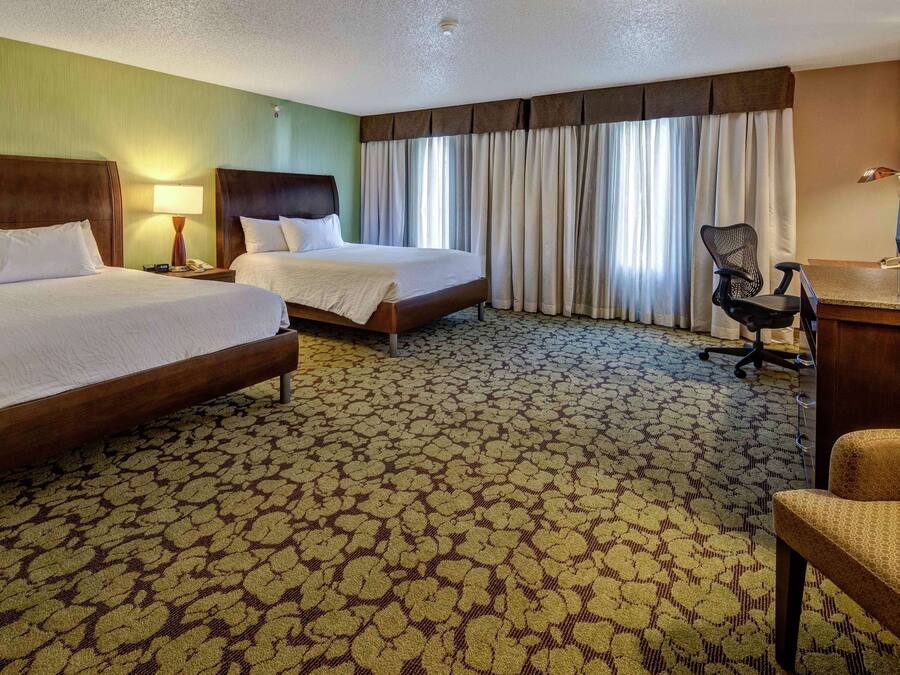 Een hotelkamer met twee bedden, een bureau met een computer en een televisie.