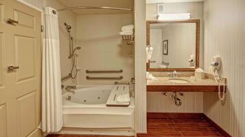 A bathroom with a bathtub, shower, vanity with a mirror, and a towel rack.