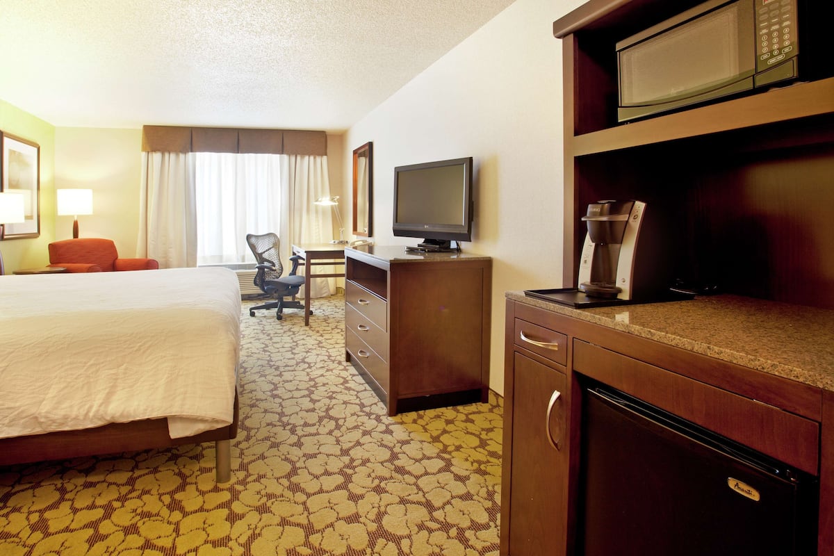 Een hotelkamer met een bed, een bureau met een televisie, een magnetron en een koffiezetapparaat.