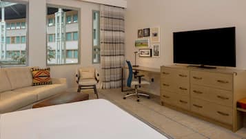 A hotel room with a bed, a desk, a chair, a television, and a wardrobe.