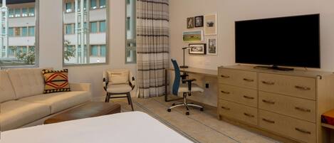 A hotel room with a bed, a desk, a chair, a television, and a wardrobe.