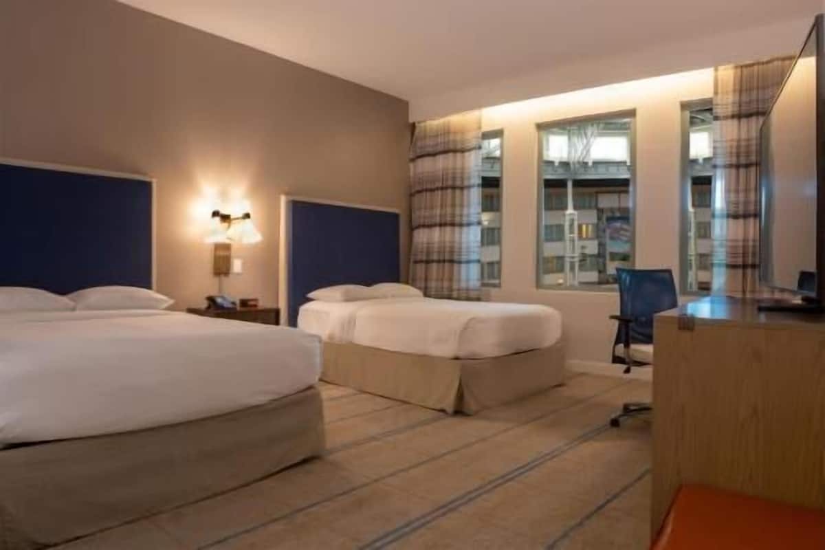 A hotel room with two beds, a desk, and a chair.
