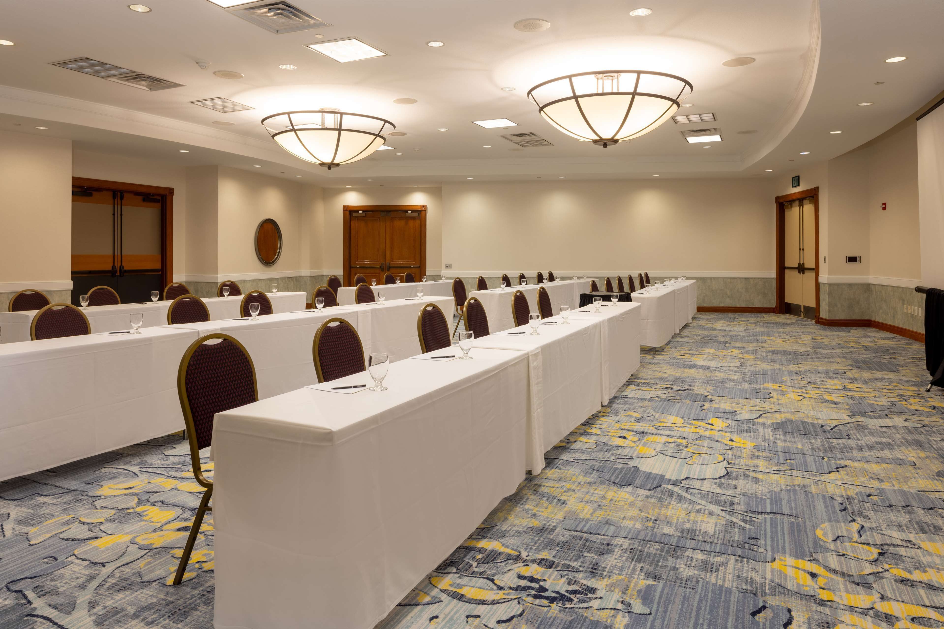 Une salle de conférence avec de longues tables, des chaises et des lustres.