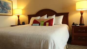 Habitación de hotel con una cama grande, dos lámparas de noche, una mesita de noche y un cuadro en la pared.