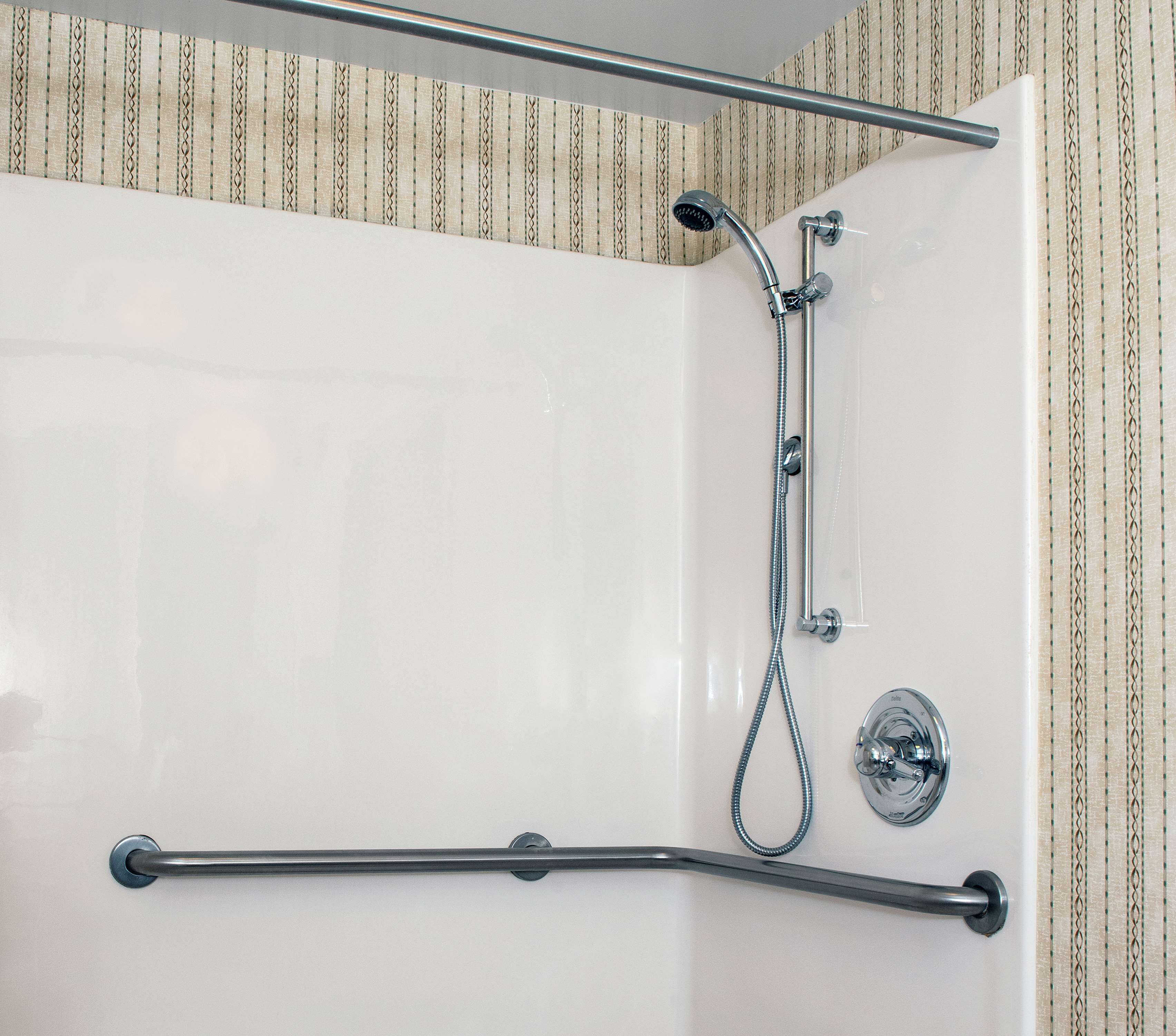 Una bañera blanca con ducha de mano y barra de apoyo.