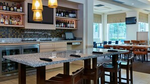 A spacious kitchen with granite countertops, wooden chairs, and a bar area with wine bottles. - Hilton Garden Inn Charlotte Pineville (Pineville)