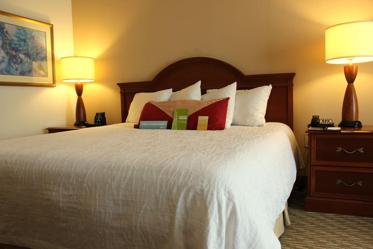 A hotel room with a large bed, two bedside tables, and a nightstand.