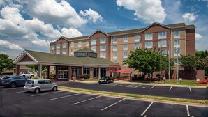 A multi-story hotel with a covered entrance, parking lot, and outdoor seating area. - Hilton Garden Inn Charlotte Pineville (Pineville)