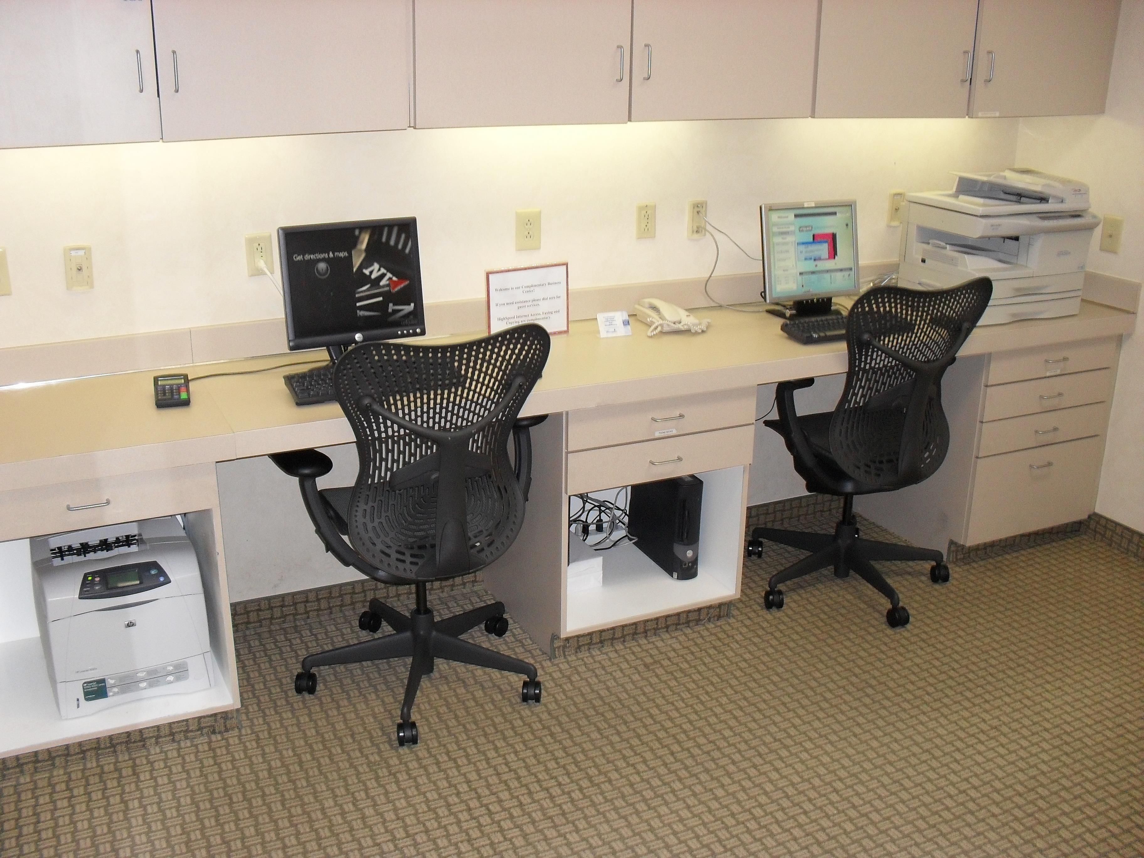 A workspace with two desks, each with a computer, a printer, and a telephone.