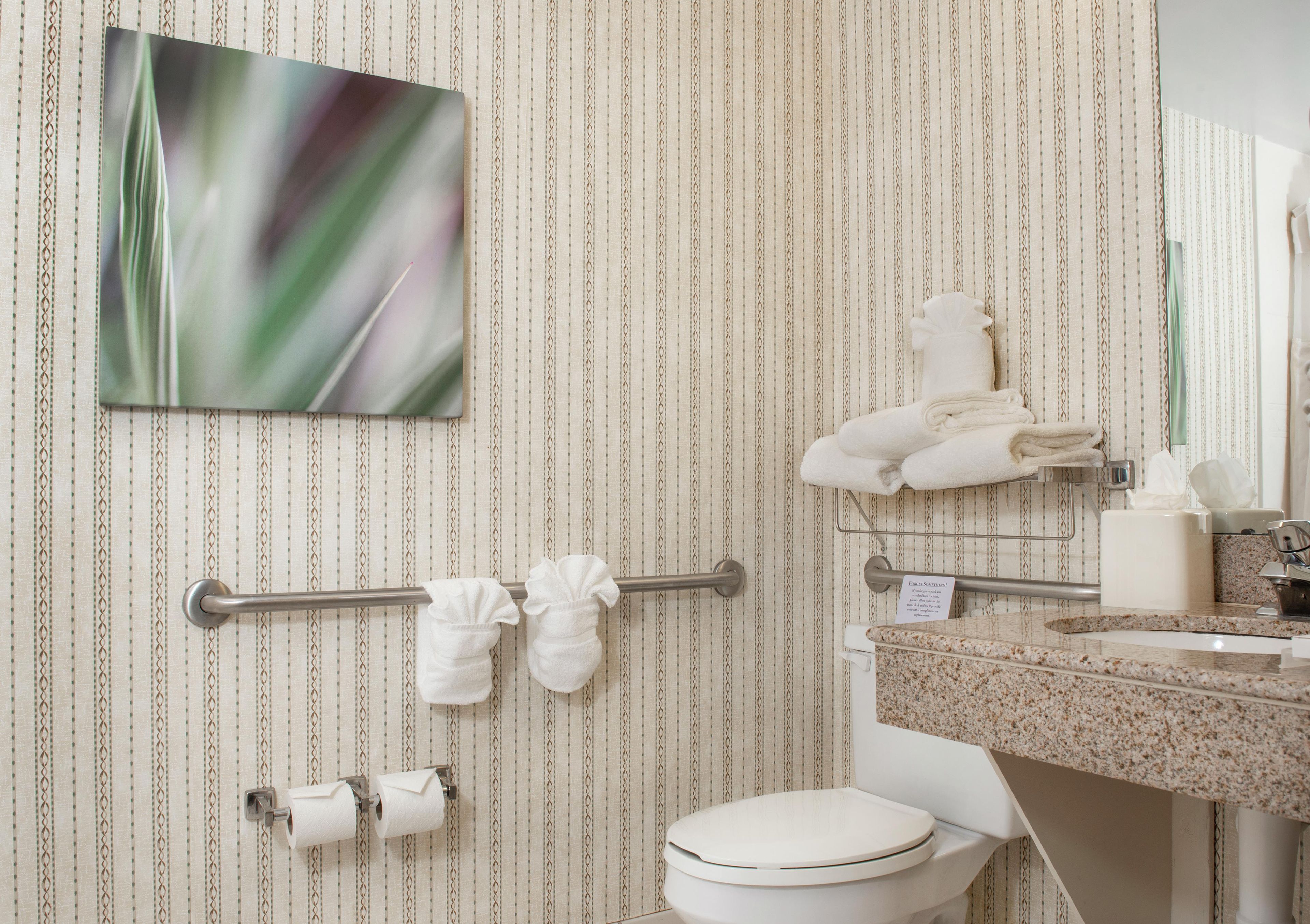 Un baño con papel tapiz a rayas, un inodoro, un perchero para toallas y un lavabo con espejo.