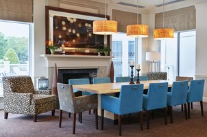 A dining area with a fireplace, blue upholstered chairs, and a wooden table.
