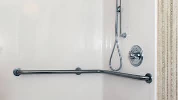 A white shower enclosure with a handheld showerhead and a handheld shower attachment.