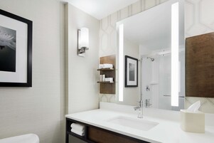 A modern bathroom with a large mirror, white sink, and a towel rack.