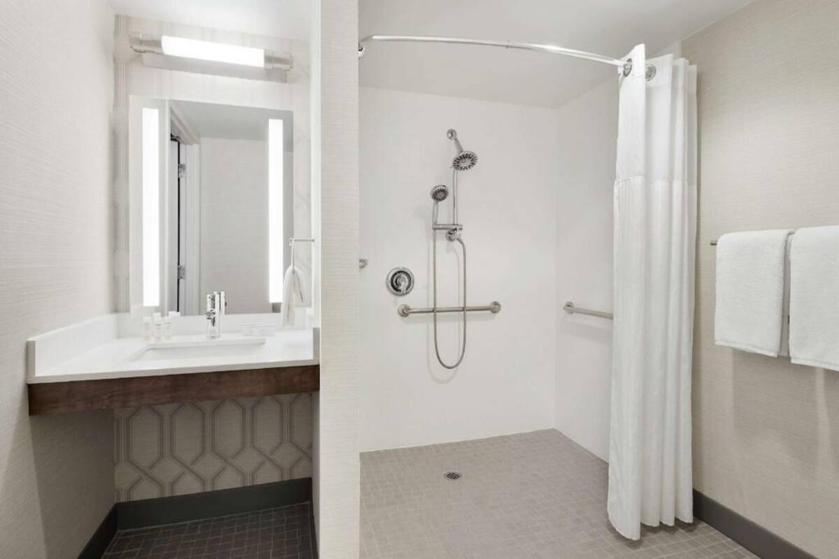 A bathroom with a shower, a sink, and a mirror.