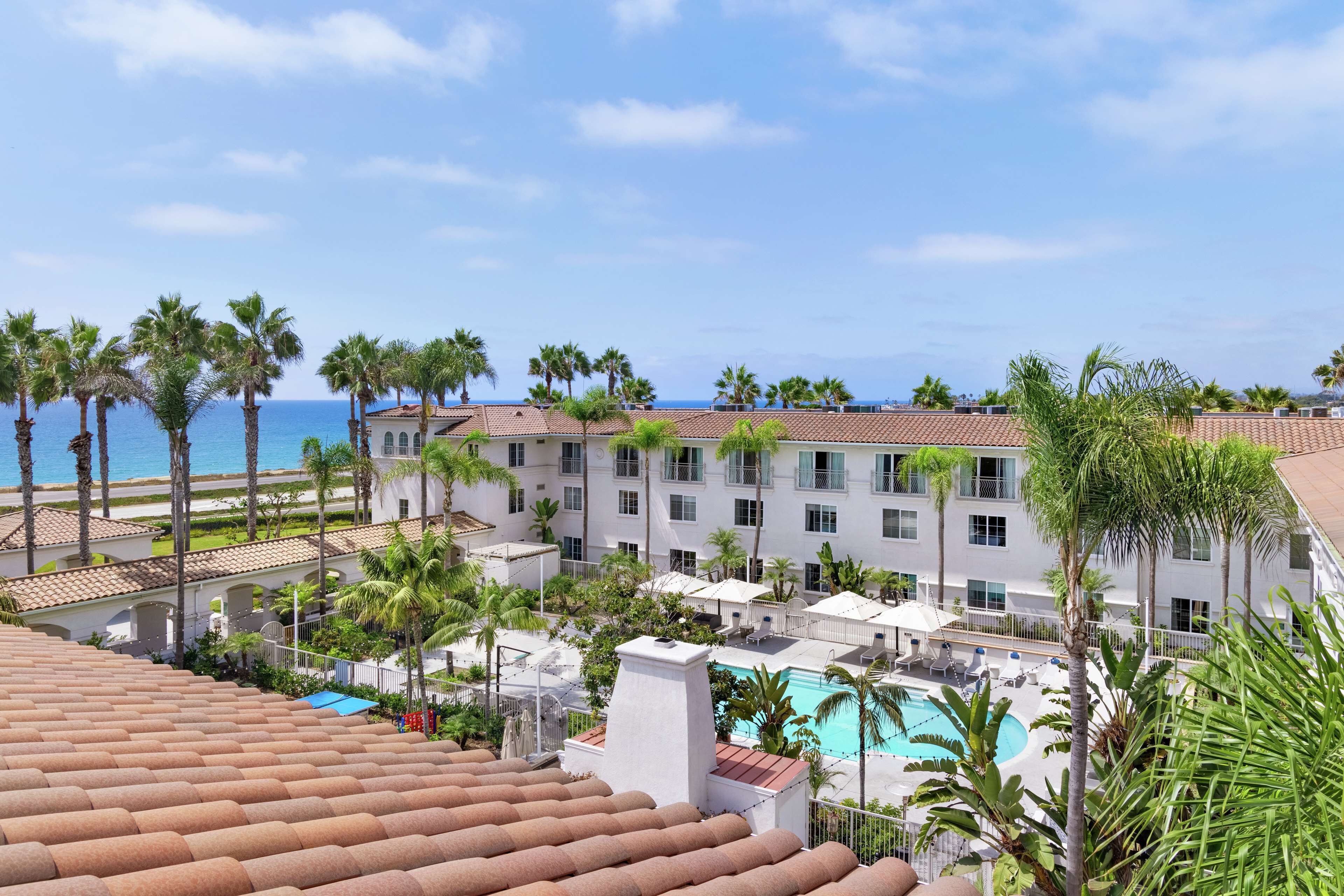 A resort with a pool, palm trees, and a view of the ocean.