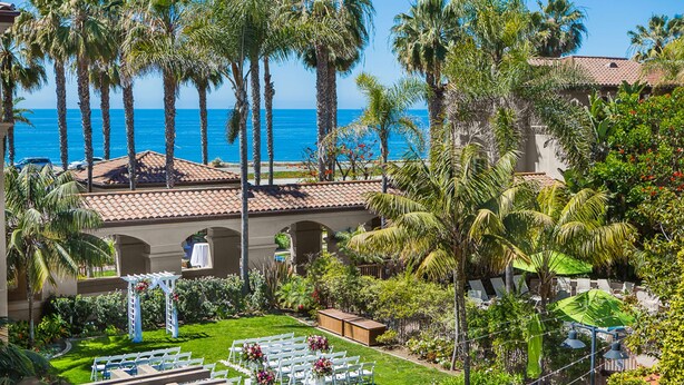 A resort with a beach view, palm trees, and a wedding ceremony setup.