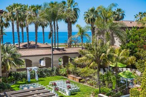 A resort with a beach view, palm trees, and a wedding ceremony setup. - Hilton Garden Inn Carlsbad Beach (Carlsbad)