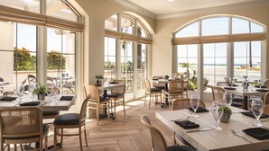 A restaurant with multiple tables and chairs, large windows, and a view of the outdoors.