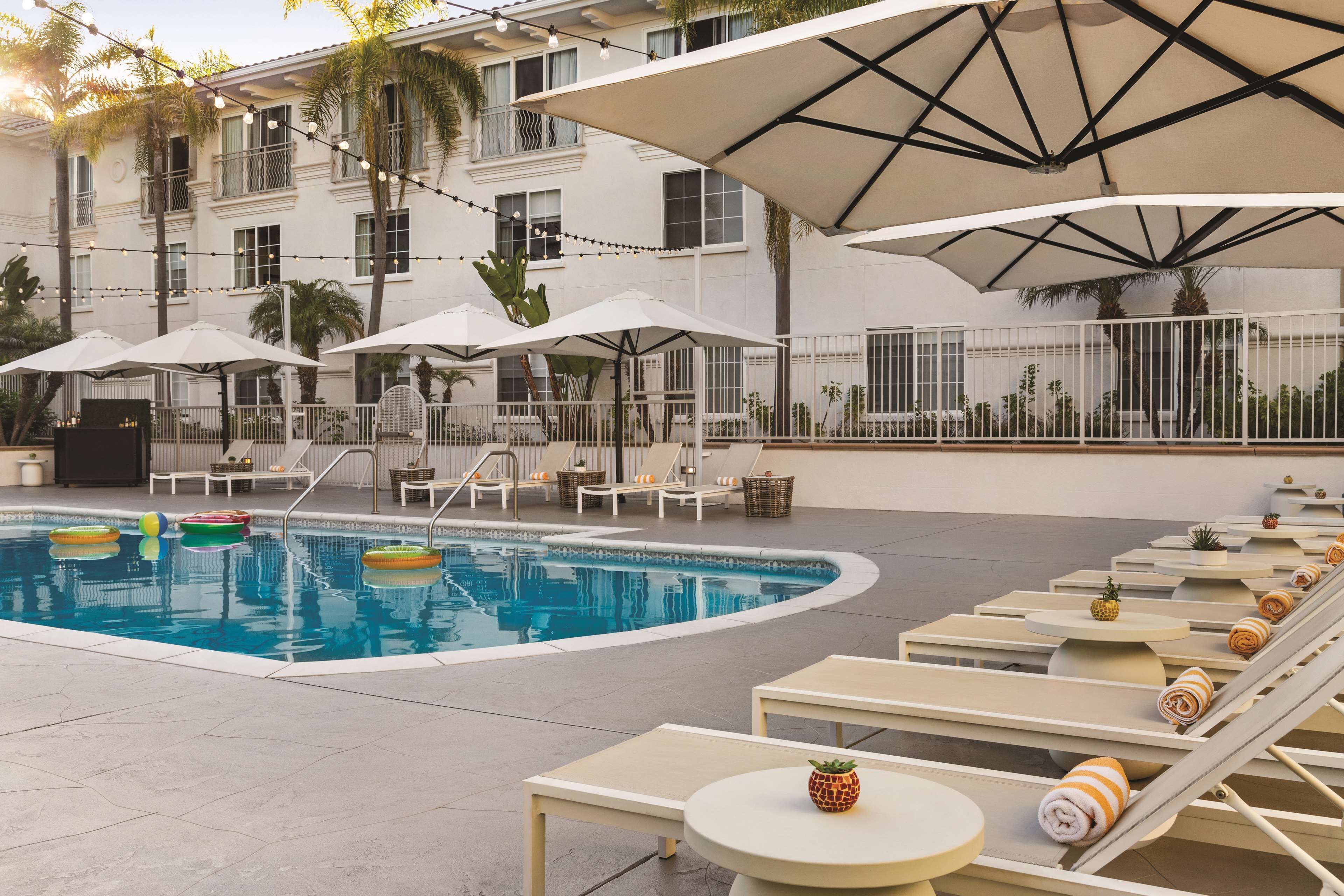 A poolside area with lounge chairs, umbrellas, and a swimming pool.