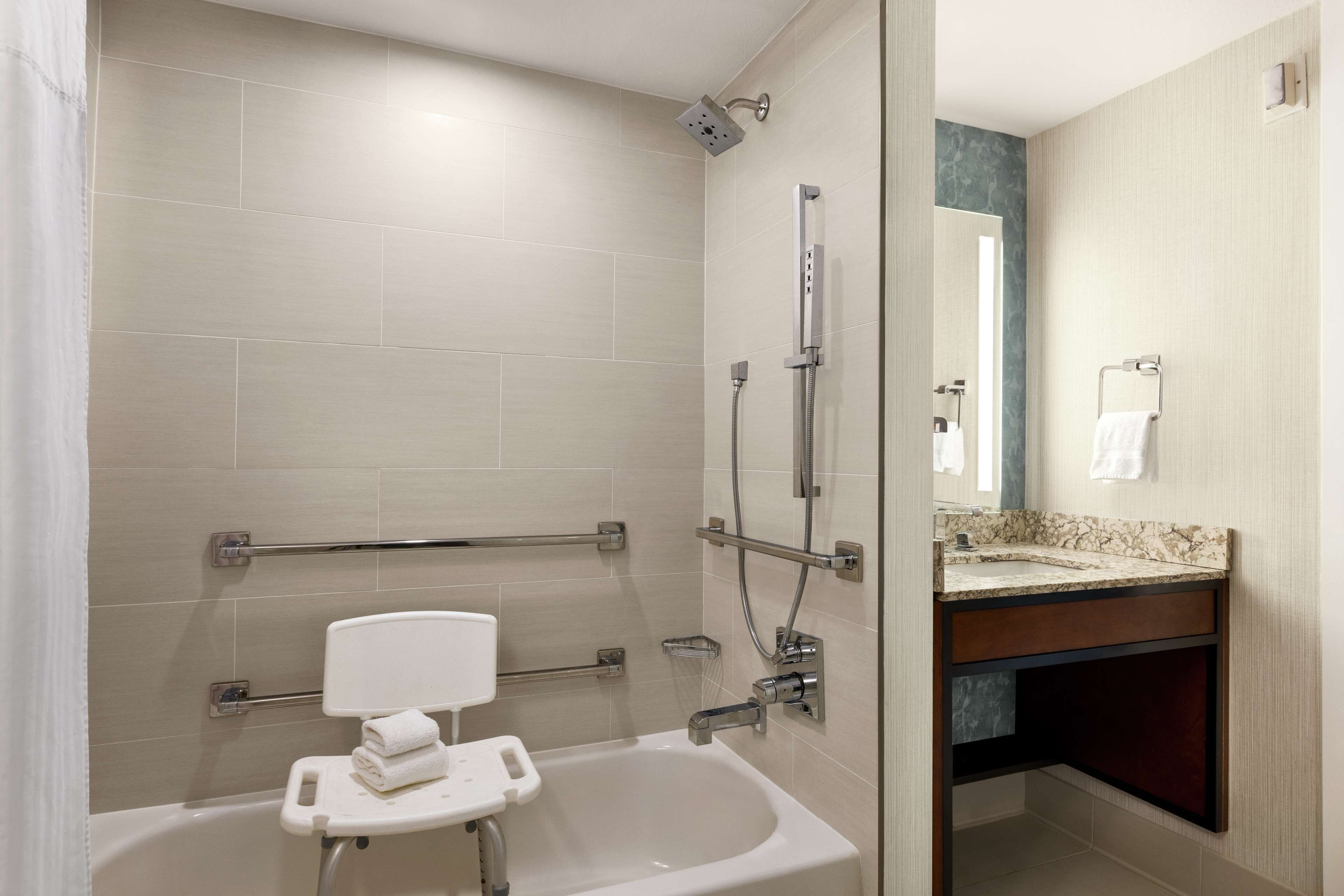Een moderne badkamer met een bad, een douche en een wastafel met een marmeren aanrechtblad.