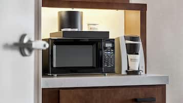 A kitchenette with a microwave, coffee maker, and a container labeled "Hilton Garden Inn."