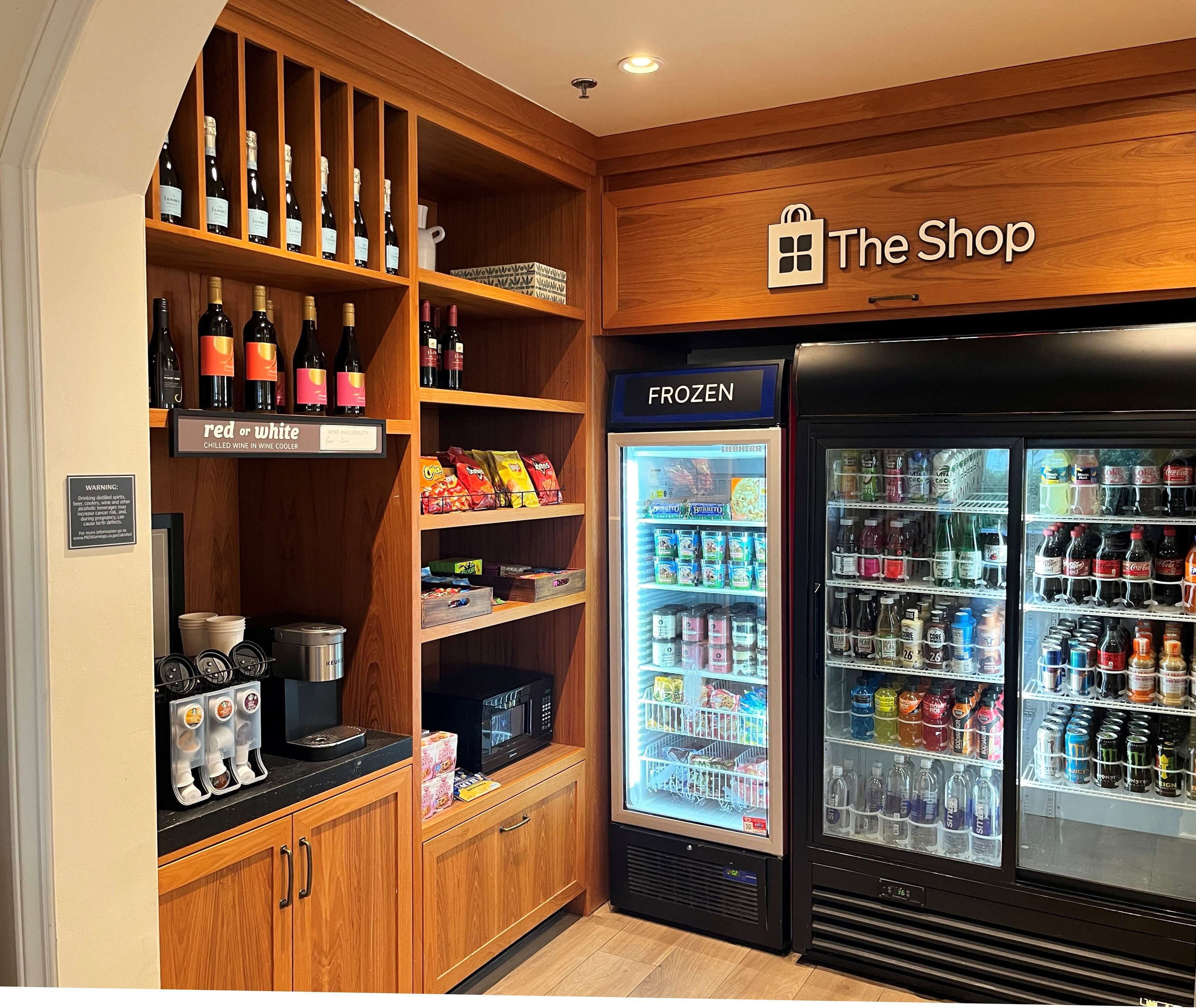 A store with shelves of wine, a freezer, and a refrigerator stocked with beverages.